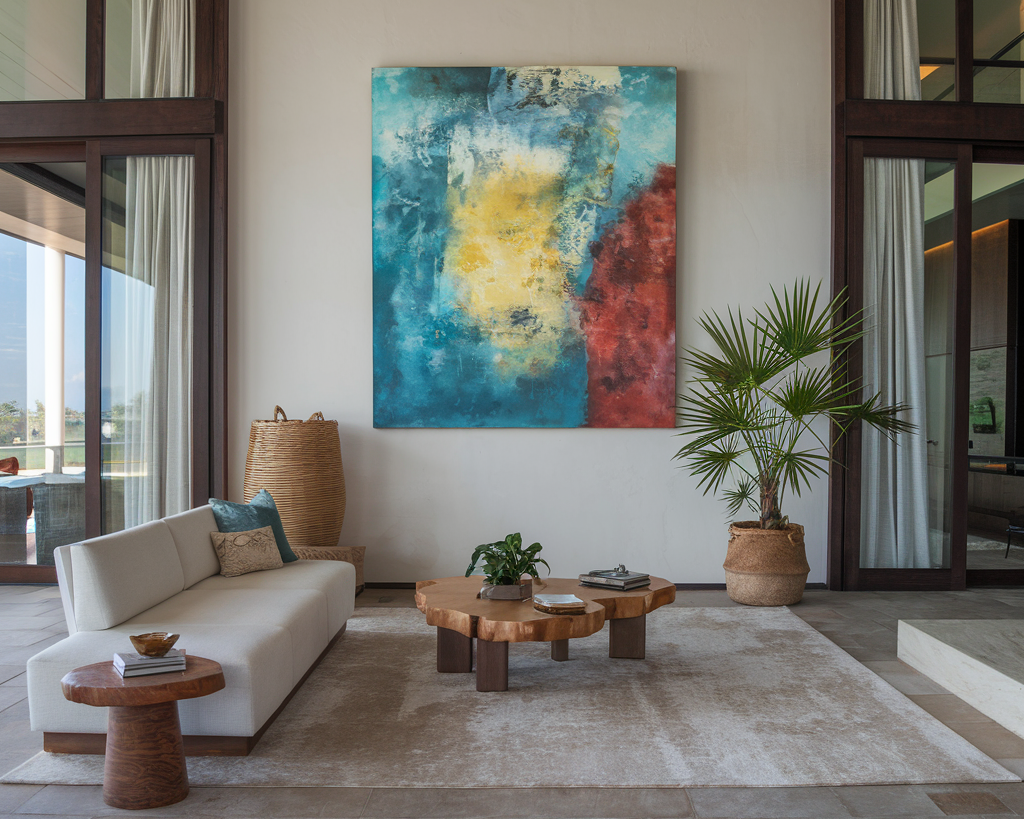 A photo of a luxury home with a living room decorated with unique finds. There is a plush white sofa with blue accents, a blue armchair with gold legs, and a green and white patterned rug.