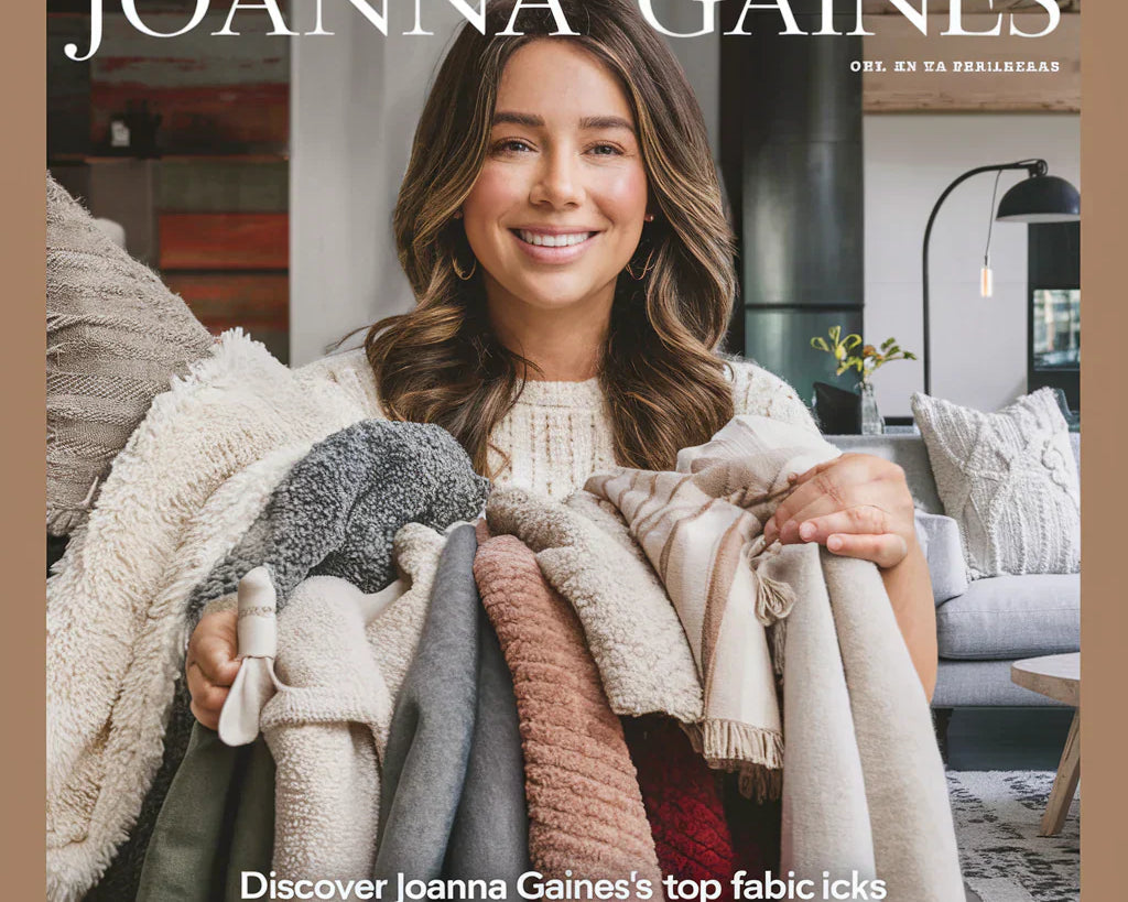 A visually stunning cover image featuring Joanna Gaines, smiling gently and holding a variety of fabrics. The fabrics include soft, cozy textures in neutral tones, with a few pops of color.