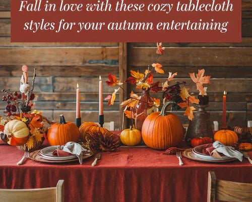 A photo of a cozy table setting with a red tablecloth and autumn-themed decorations. There are pumpkins, leaves, and candles on the table. The background is a rustic wooden wall