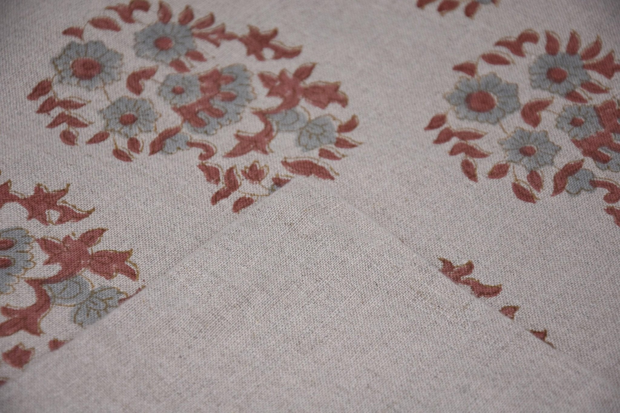 Close-up of floral fabric with red and blue flowers on beige background.