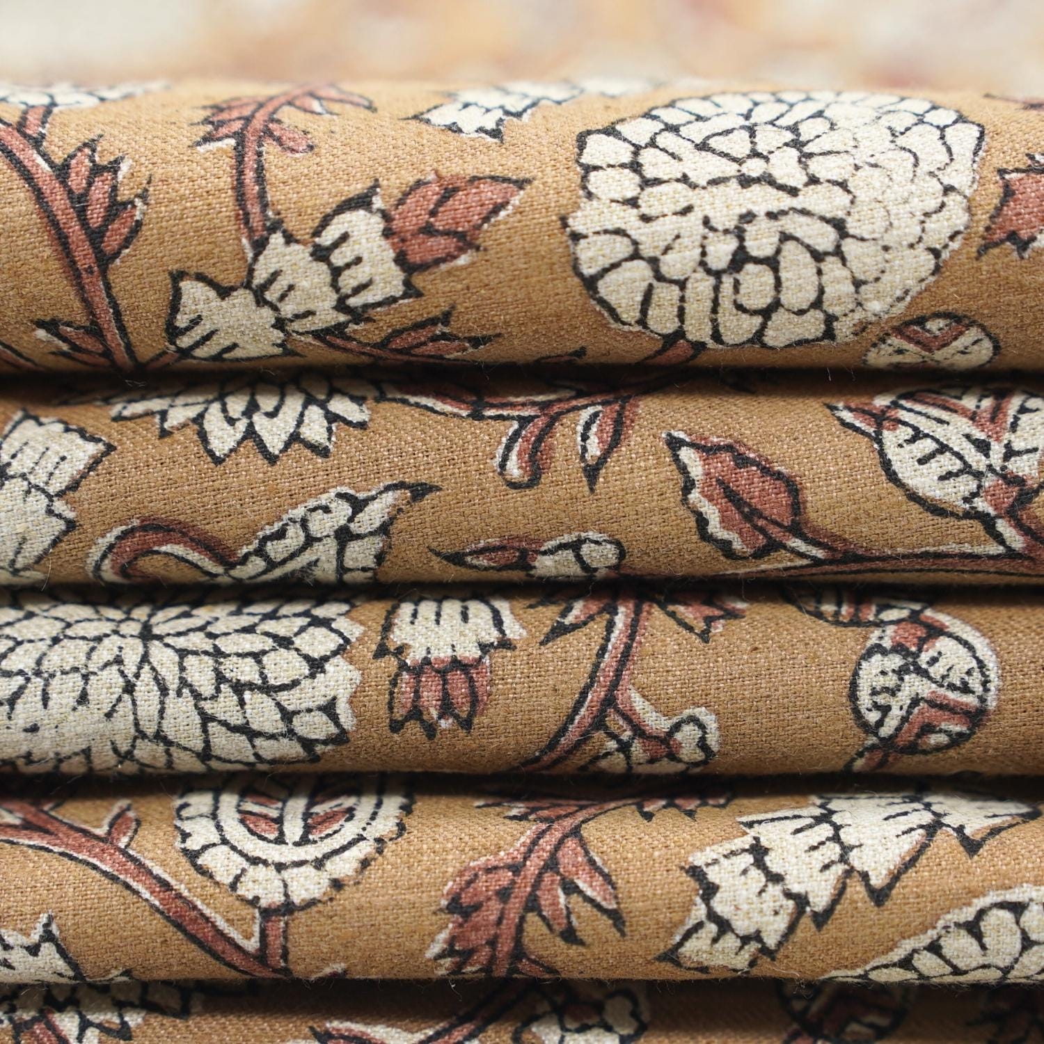Gopi floral print in brown color showcased on natural linen blend, styled in tablecloths and cushion sets for festive decor themes.