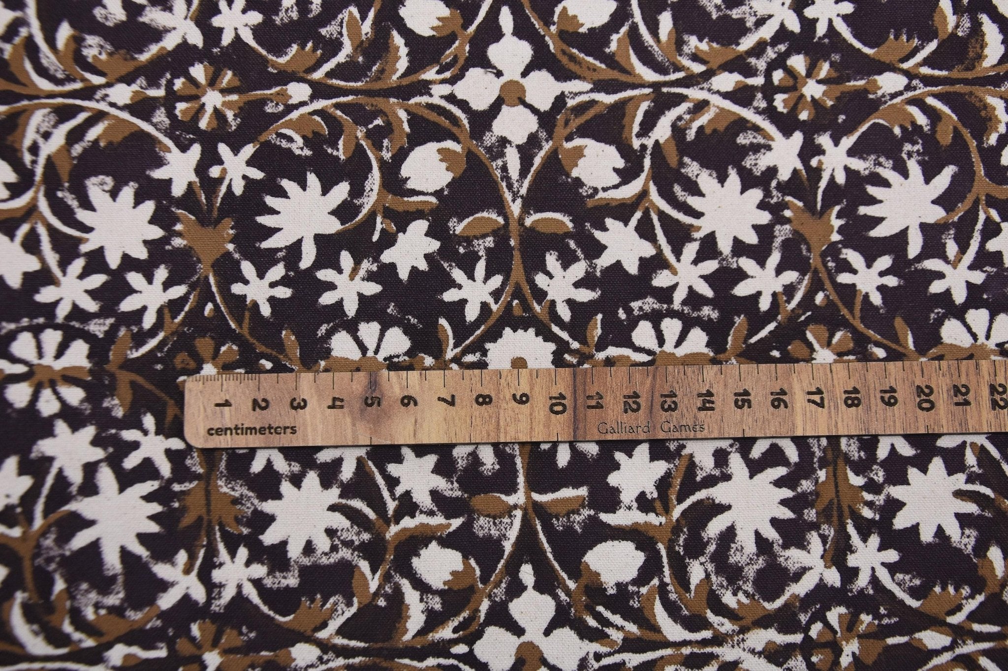 Floral patterned fabric with a ruler for scale on a dark background