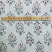 Fabric with a decorative pattern and a wooden ruler for scale.