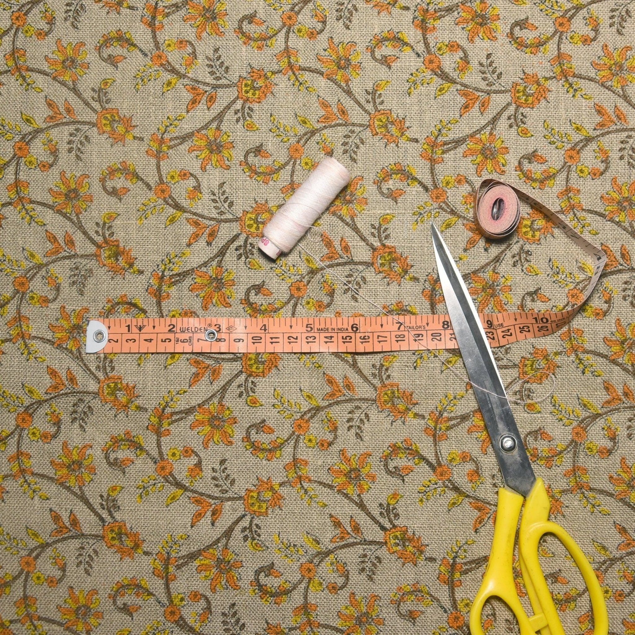 Floral-patterned fabric with a measuring tape and scissors on top