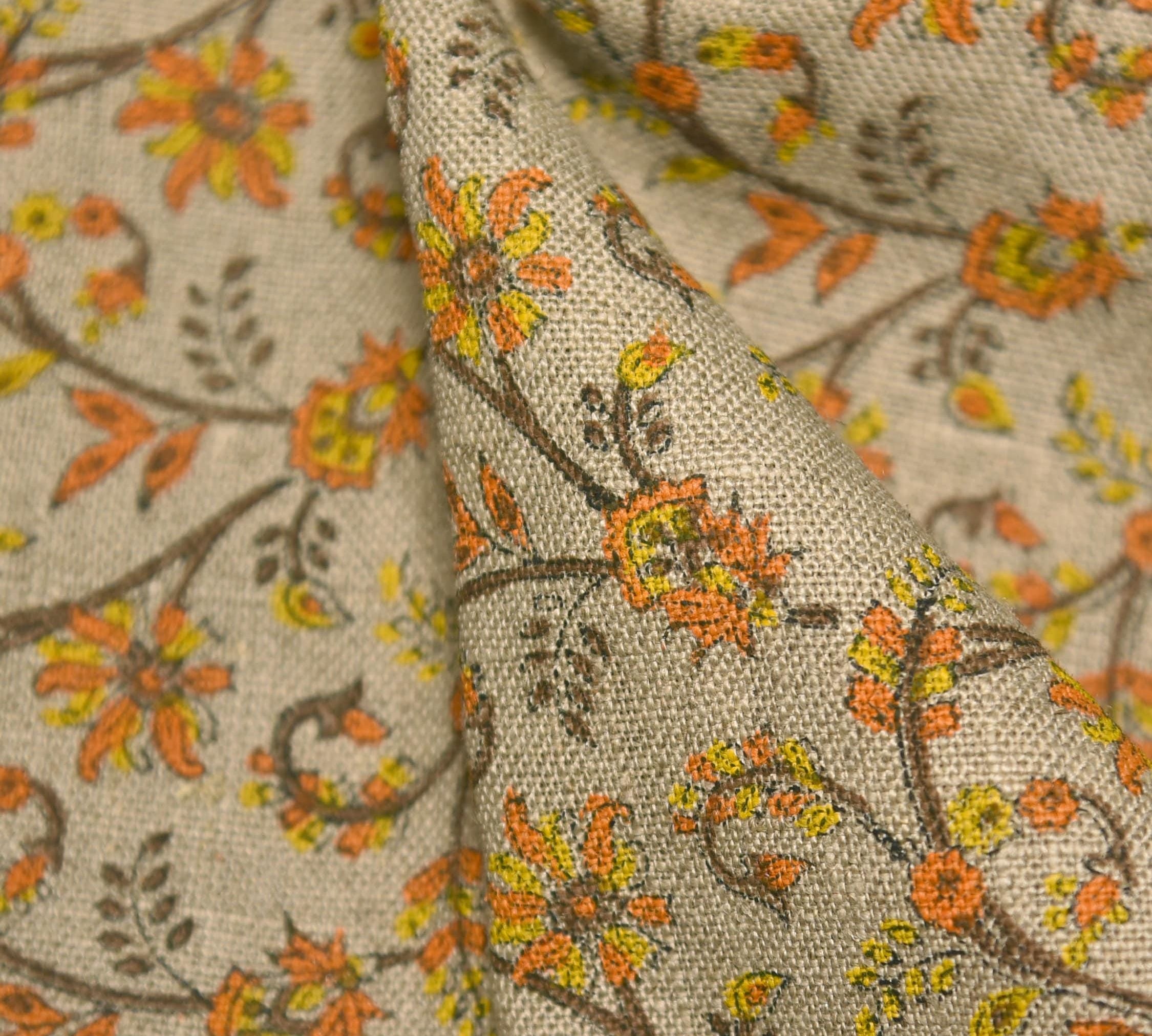 Close-up of floral fabric with orange, yellow, and brown colors on a beige background