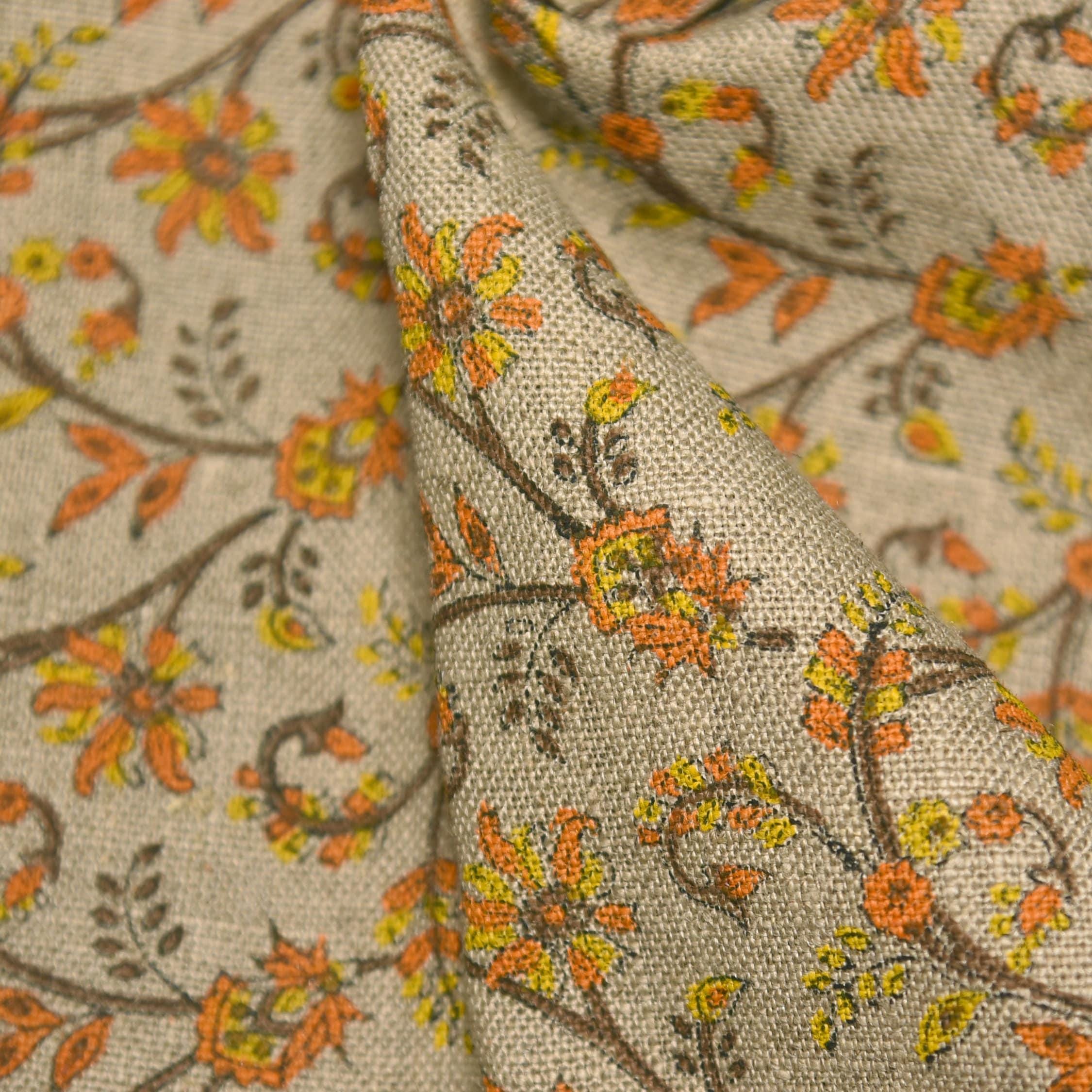 Close-up of floral fabric with orange, yellow, and brown colors on a beige background