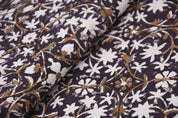 Close-up of patterned fabric with white and brown floral design on a dark background
