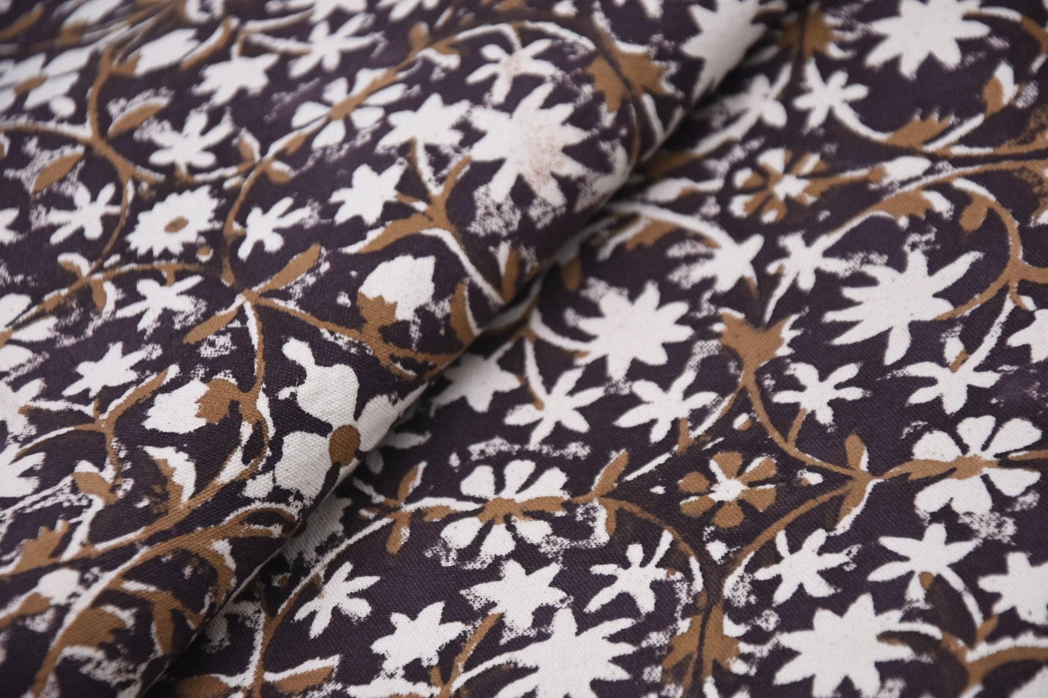 Close-up of patterned fabric with white and brown floral design on a dark background
