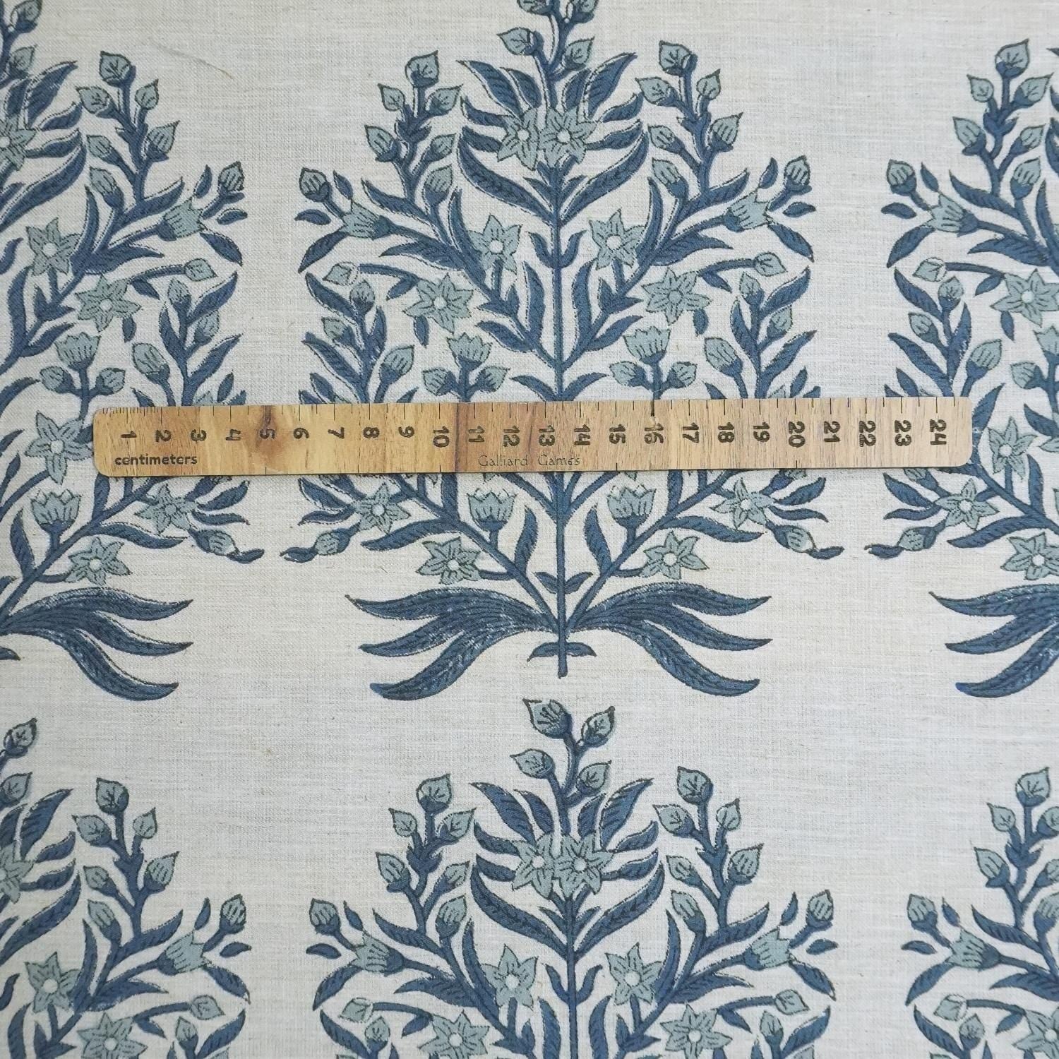 Fabric with blue floral pattern and a wooden ruler for scale on a white background