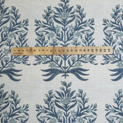Fabric with blue floral pattern and a wooden ruler for scale on a white background