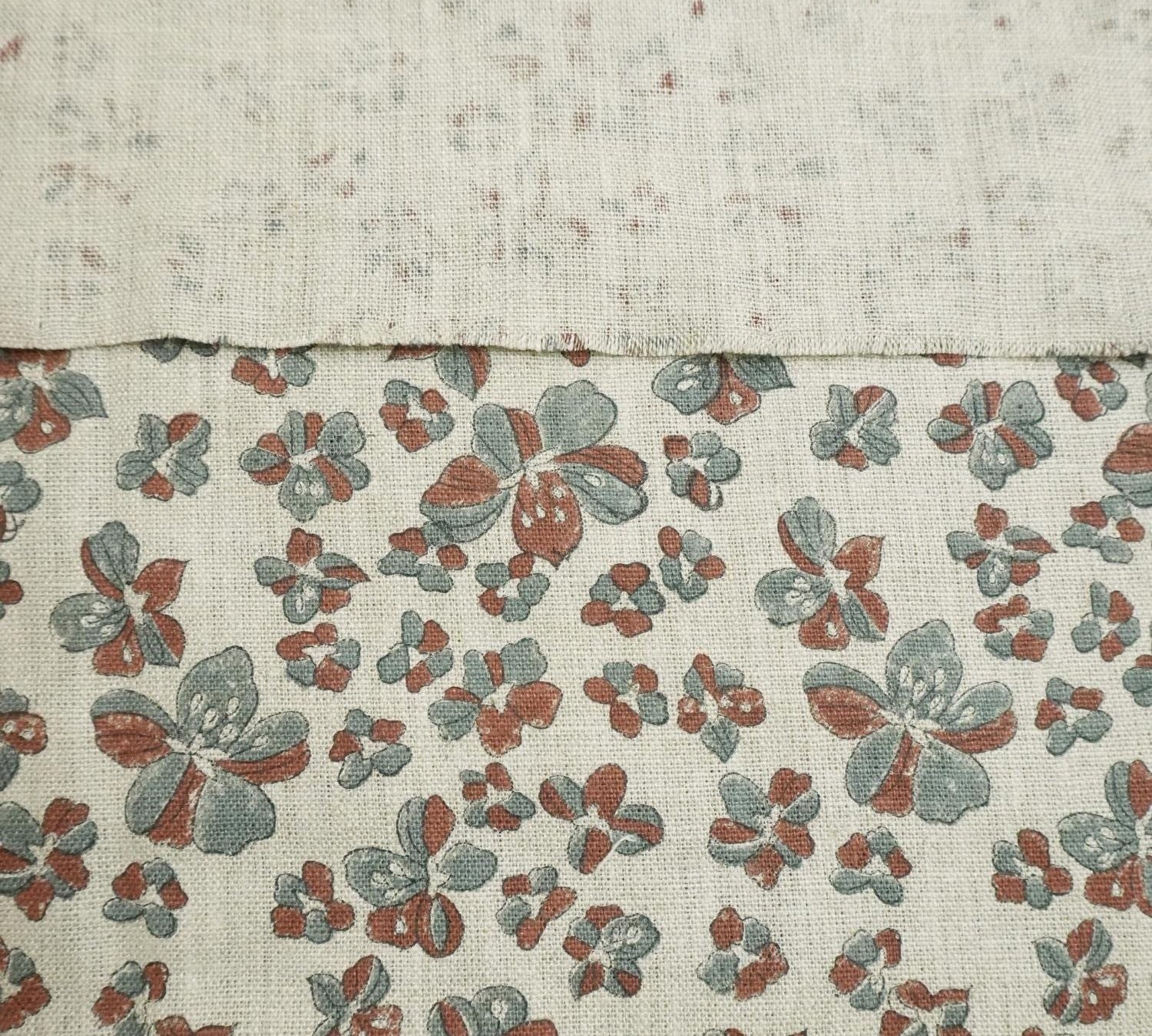 Two fabric swatches, one plain and one with a floral pattern, on a textured beige background.