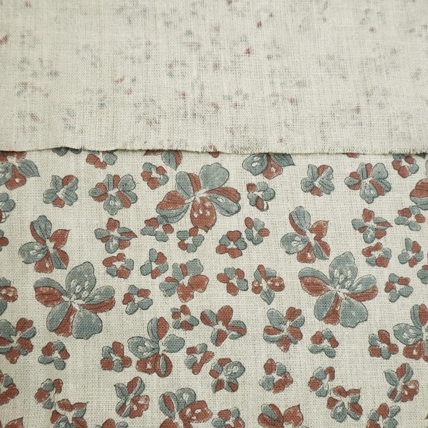 Two fabric swatches, one plain and one with a floral pattern, on a textured beige background.