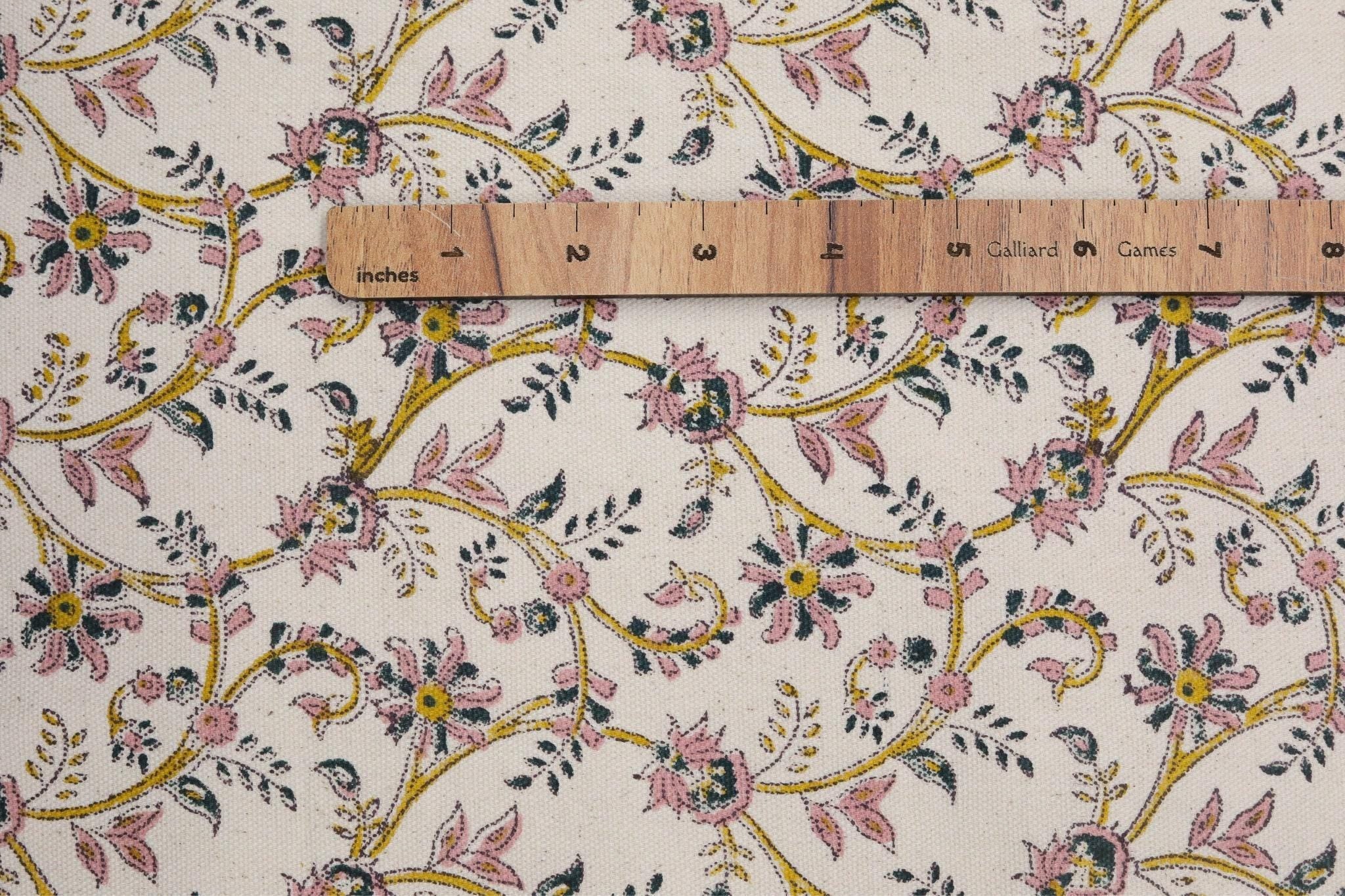 Floral patterned fabric with a wooden ruler for scale on a beige background