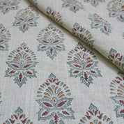 Fabric with a pattern of geometric shapes in red, green, and brown on a beige background.