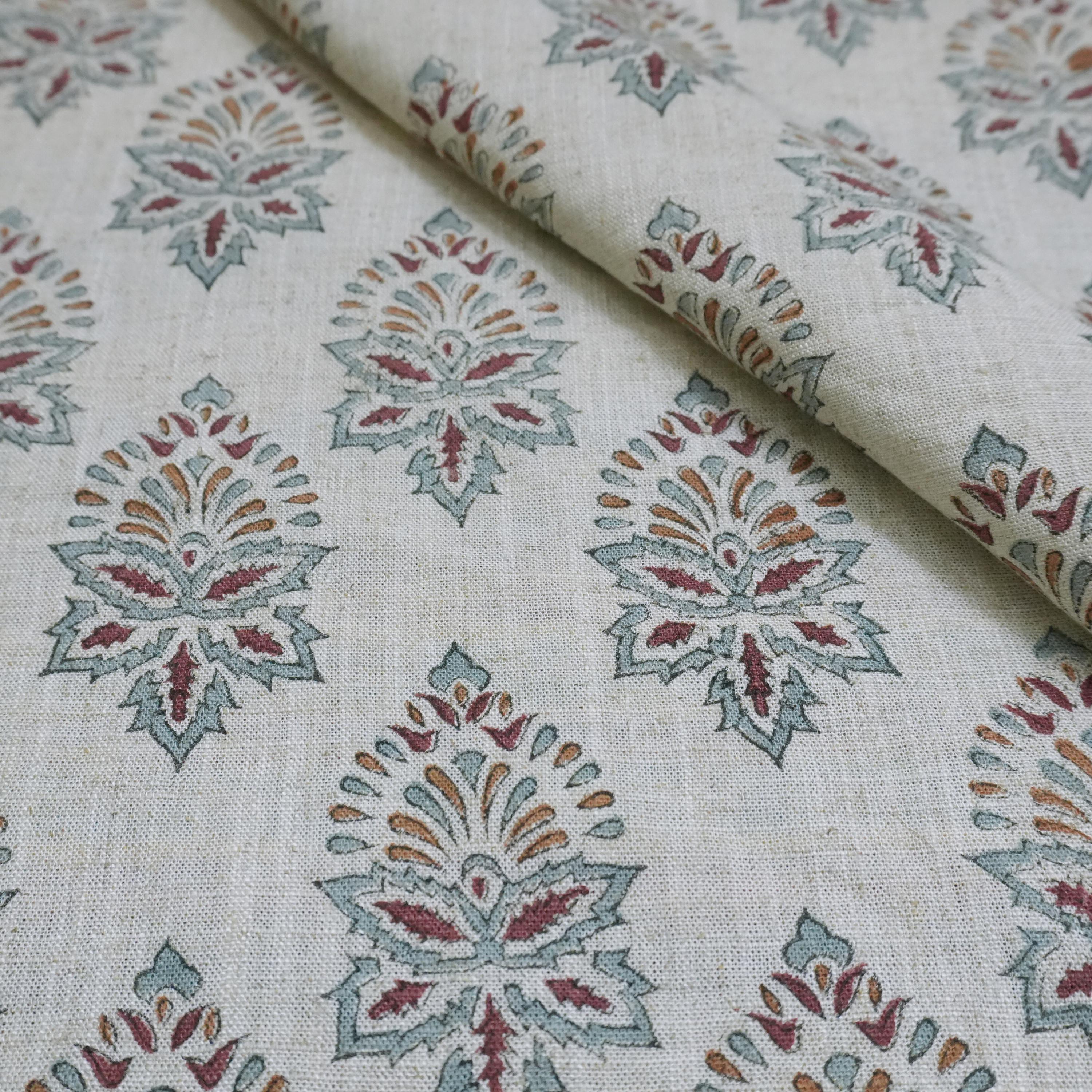 Fabric with a pattern of geometric shapes in red, green, and brown on a beige background.