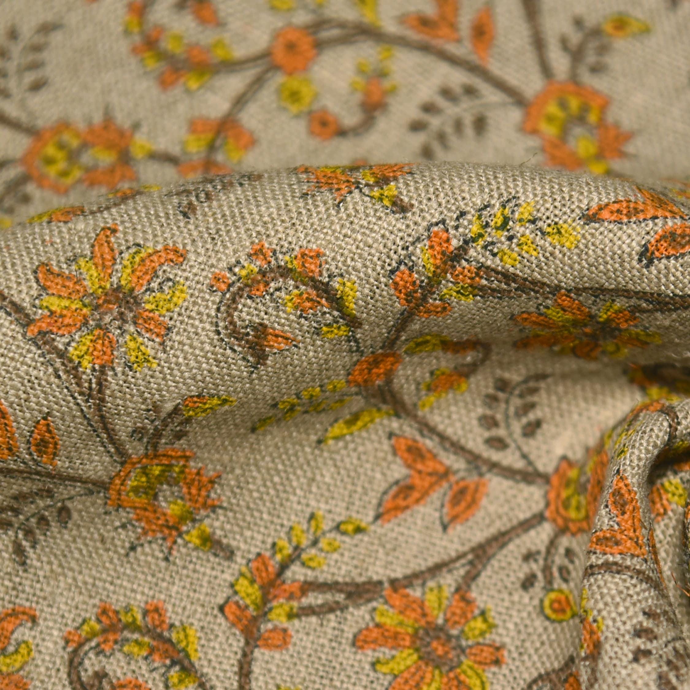 Close-up of floral fabric with orange, yellow, and green flowers on a beige background